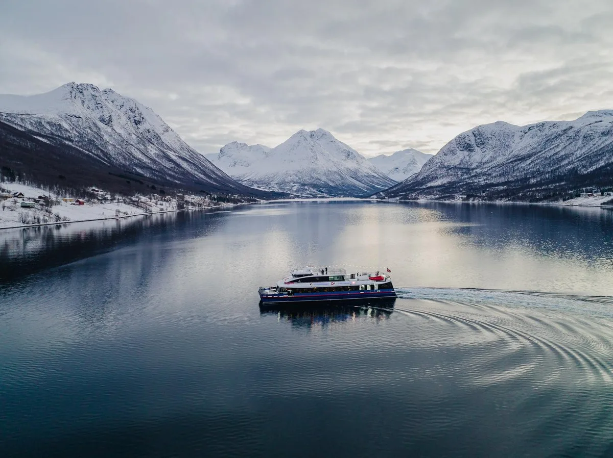 Catamaran on calm water between snowy mountains